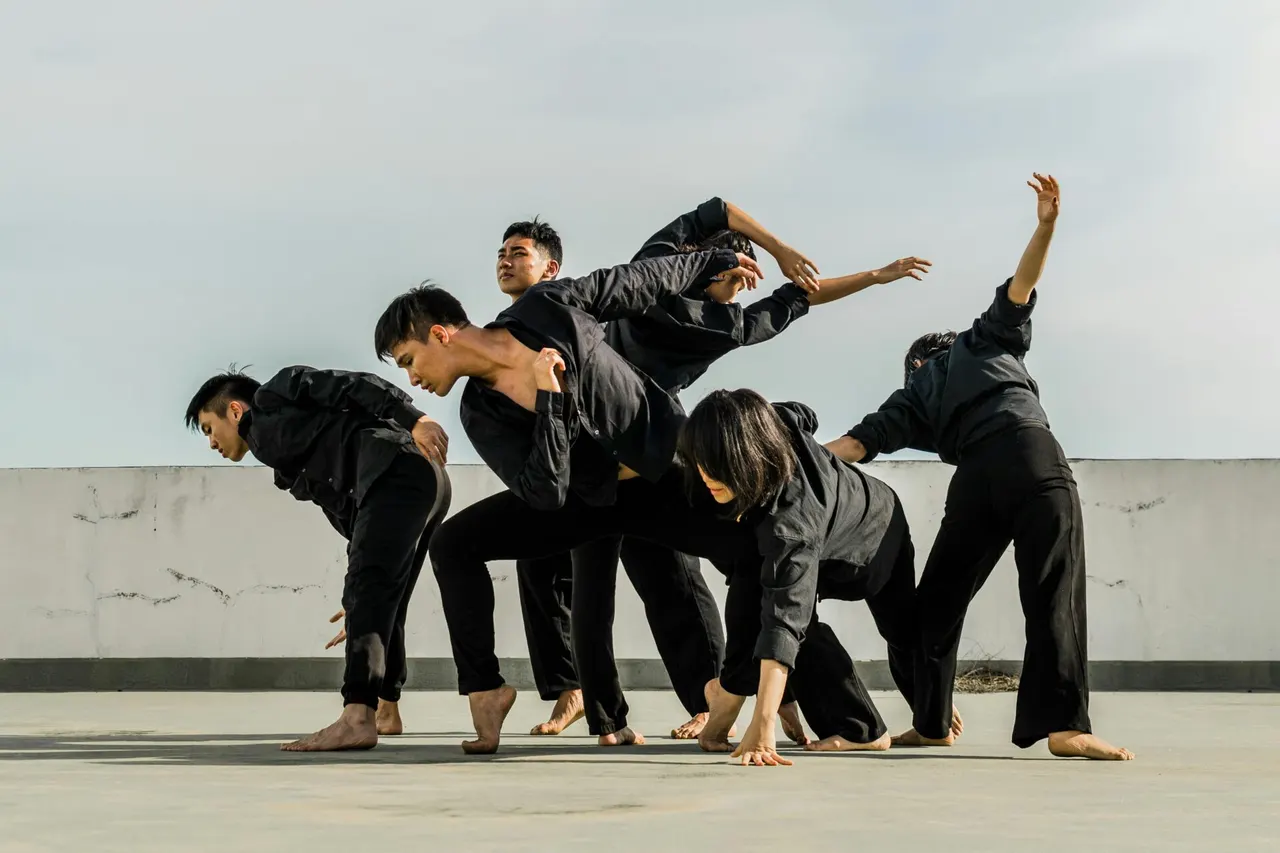 Dancers in black stretching together on a rooftop