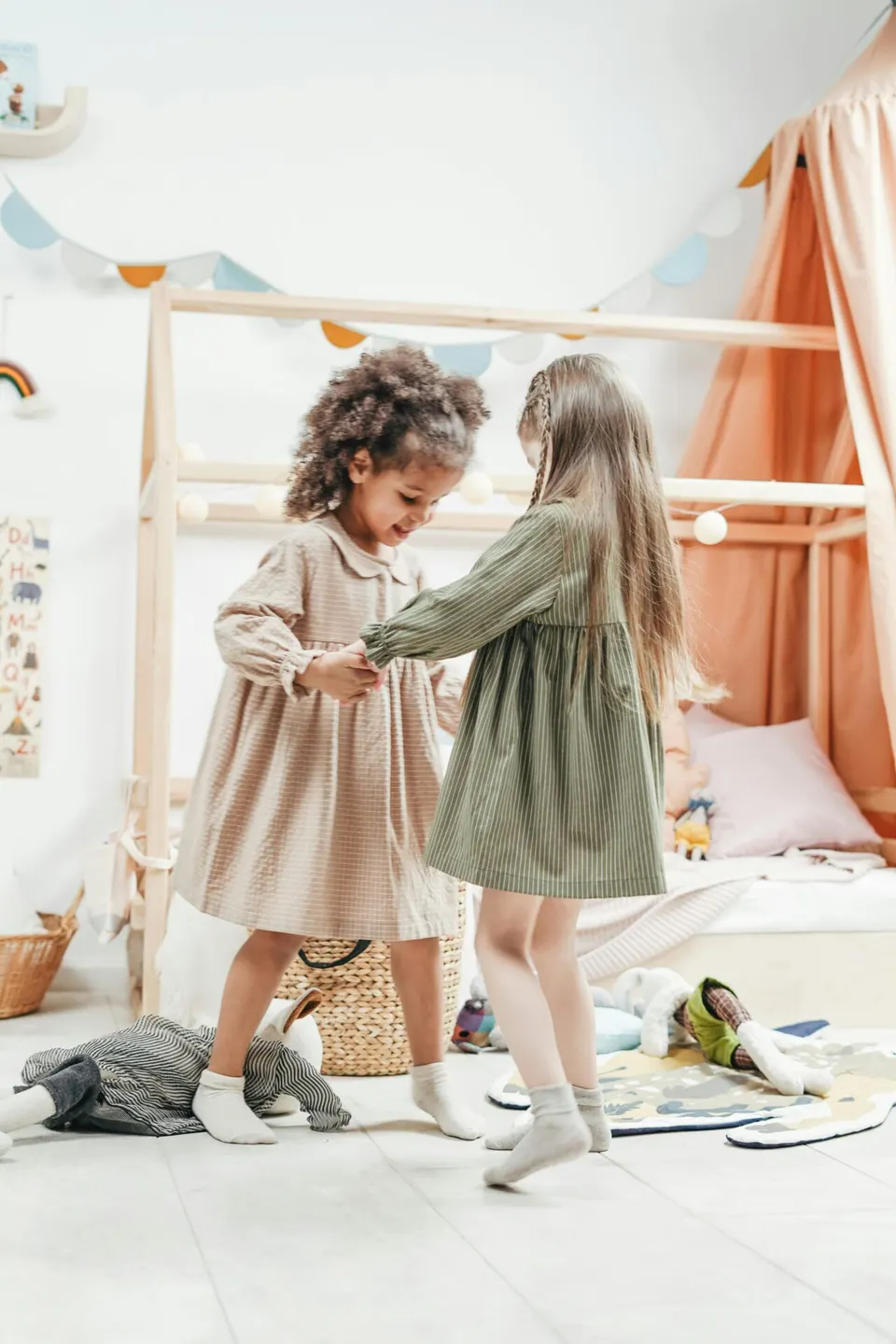 Two young girls dancing together in a playroom